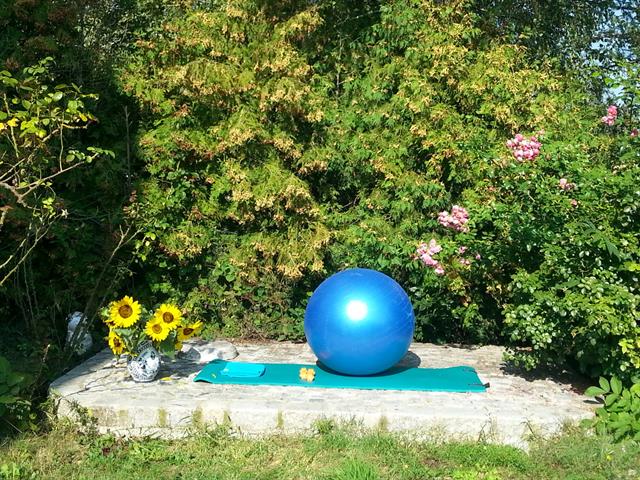 eine blaue Kugel auf einer Steinplattform vor einem Garten